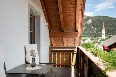 a balcony with a table and a chair and a window at Christlrumerhof in Brunico