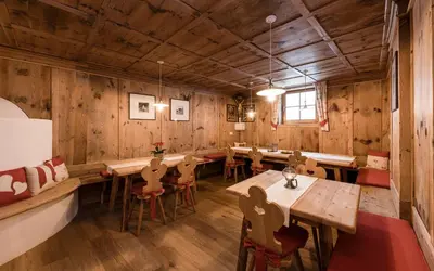 a restaurant with wooden walls and tables and chairs at Christlrumerhof in Brunico
