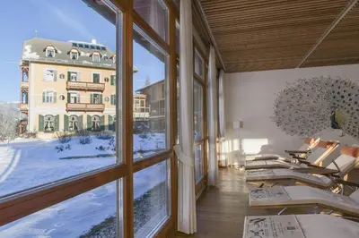 a room with large windows with a view of a building at Hotel Monte Sella in San Vigilio Di Marebbe