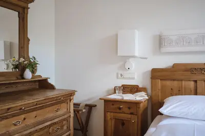 a bedroom with a bed and a wooden dresser at Hotel Monte Sella in San Vigilio Di Marebbe