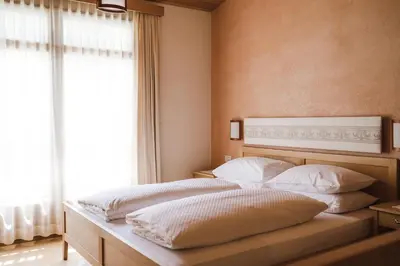 a bedroom with a bed with white pillows and a window at Hotel Monte Sella in San Vigilio Di Marebbe