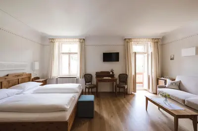 a bedroom with two beds and a couch and a table at Hotel Monte Sella in San Vigilio Di Marebbe