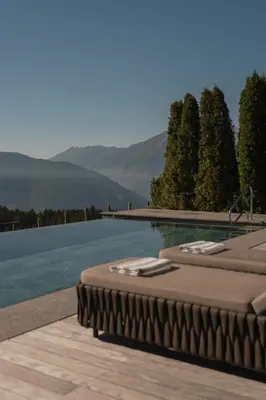 a swimming pool with two lounge chairs next to a lake at Chalet Mirabell in Avelengo