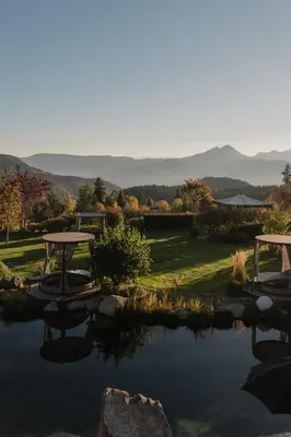 a pond with a picnic tables and mountains in the background at Chalet Mirabell in Avelengo