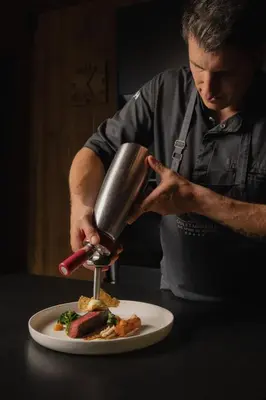 a man is preparing a plate of food on a table at Chalet Mirabell in Avelengo