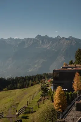 a building on a hill with mountains in the background at Chalet Mirabell in Avelengo