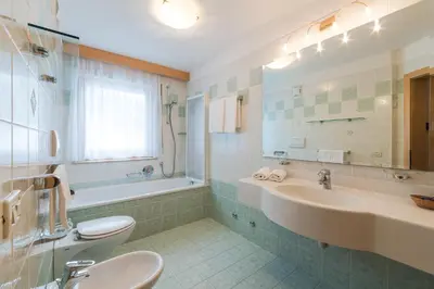 a bathroom with a sink and a tub and a toilet at Residence Chalet Pinis in Corvara in Badia