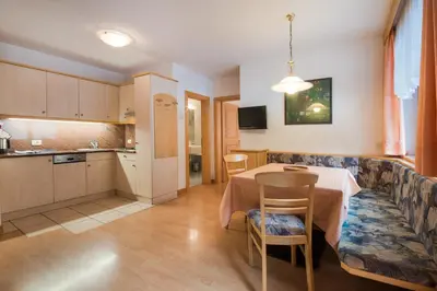 a kitchen and a dining room with a table and chairs at Residence Chalet Pinis in Corvara in Badia