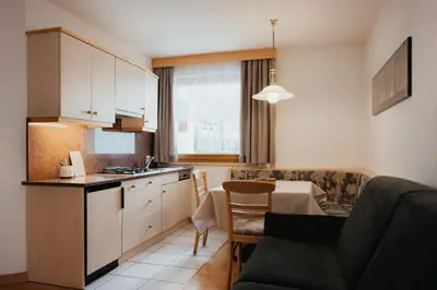a kitchen and a living room with a table at Residence Chalet Pinis in Corvara in Badia