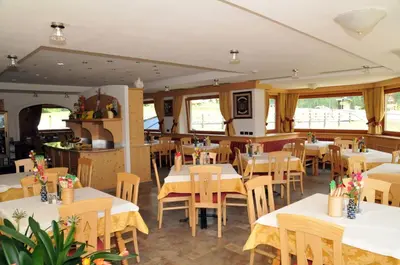 a restaurant with white tables and chairs and windows at Hotel Ciamol in Mazzin