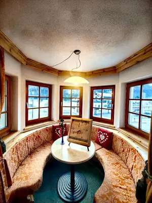 a living room with couches and a table and windows at Hotel Ciamol in Mazzin