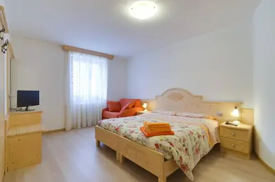 a bedroom with a bed and a couch and a television at Agritur Belsogno B&B in Brez