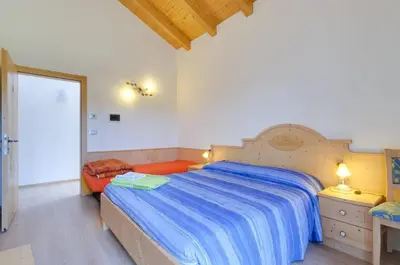 a bedroom with a large bed with a blue comforter at Agritur Belsogno B&B in Brez