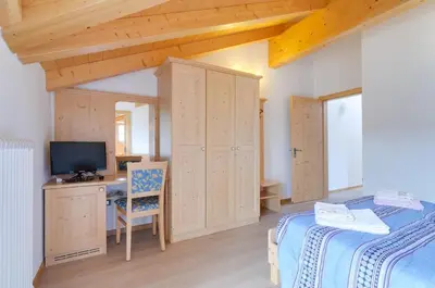 a bedroom with a bed and a desk with a television at Agritur Belsogno B&B in Brez