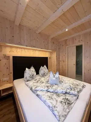a bedroom with a large bed in a wooden room at Mesnerhof my Paradise in Fiè