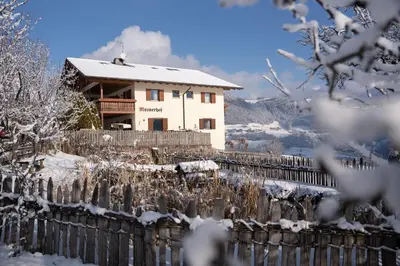 a house covered in snow in front of a fence at Mesnerhof my Paradise in Fiè