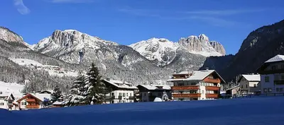 a town with snow covered mountains in the background at Cesa Bernard in Pozza di Fassa