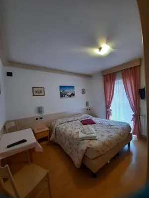 a bedroom with a bed and a table and a window at Cesa Bernard in Pozza di Fassa