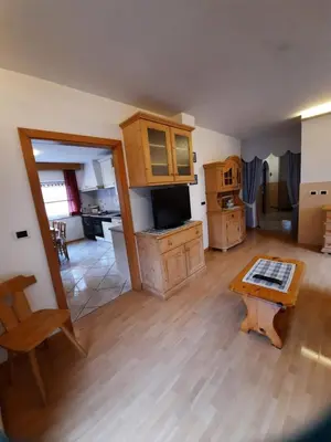 a living room with a table and a kitchen at Cesa Bernard in Pozza di Fassa
