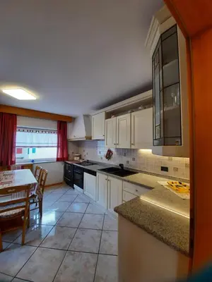 a kitchen with white cabinets and a table in it at Cesa Bernard in Pozza di Fassa