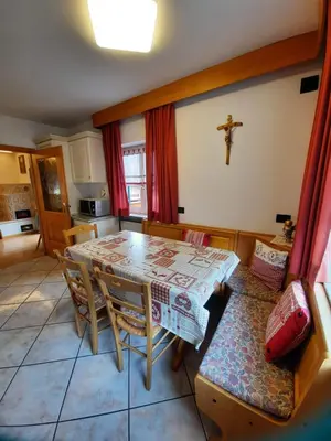 a kitchen with a table and a cross on the wall at Cesa Bernard in Pozza di Fassa