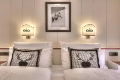 a bedroom with two beds and two lights on the wall at Hotel Luianta in Colfosco
