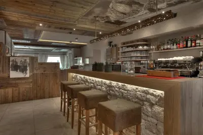 a bar with a row of bar stools at Hotel Luianta in Colfosco