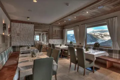 a restaurant with tables and chairs and a large window at Hotel Luianta in Colfosco