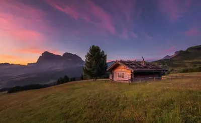 a bedroom with a bed and a balcony at Hotel Goldknopf in Alpe di Siusi