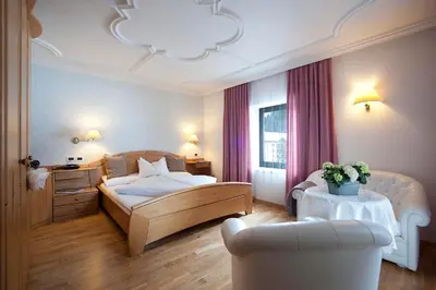 a hotel room with a bed and a chair at Hotel Italia in Corvara in Badia