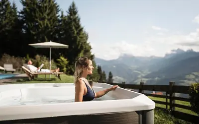 a woman sitting in a bath tub with a view at Granpanorama Wellnesshotel Sambergerhof Superior in Villandro