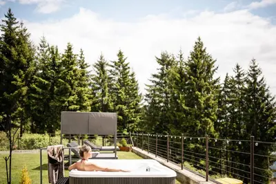 a woman sitting in a bath tub on a patio at Granpanorama Wellnesshotel Sambergerhof Superior in Villandro