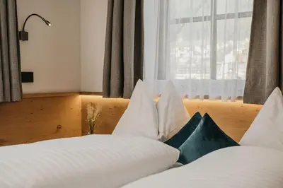 a bedroom with a bed with white pillows and a window at Miraval Perathoner Andreas in Ortisei