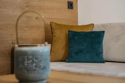 a couch with a blue pillow and a candle on a table at Miraval Perathoner Andreas in Ortisei