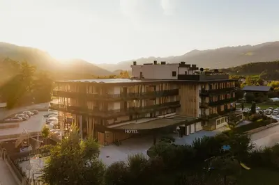 a building with the sun setting behind a mountain at Hotel B&B Feldmessner in Brunico