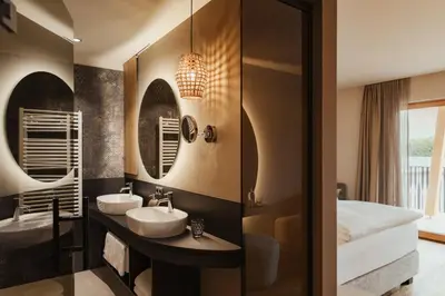 a bathroom with two sinks and a bed at Hotel B&B Feldmessner in Brunico