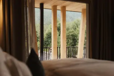 a bedroom with a large window with a view of a porch at Hotel B&B Feldmessner in Brunico