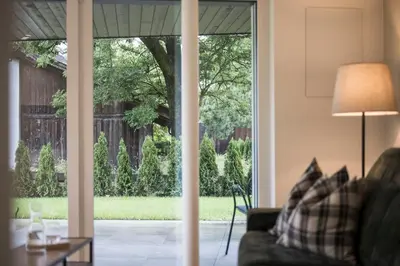 a living room with a sliding glass door looking out at a yard at Astor Apartments in Valdaora
