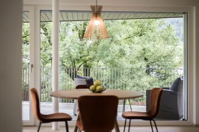 a dining room with a table and chairs and a large window at Astor Apartments in Valdaora