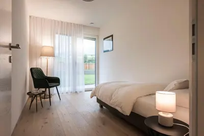 a bedroom with a bed and a chair and a window at Astor Apartments in Valdaora