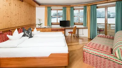 a hotel room with two beds and a desk at Astor Apartments in Valdaora