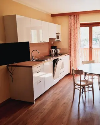 a kitchen with white cabinets and a table and a dining room at Residence Hofer in Bressanone