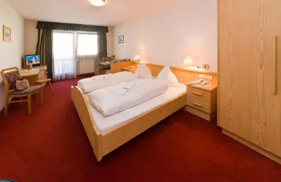a bedroom with a white bed with white pillows at Hotel Seppi in Mühlbach