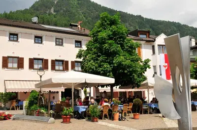 a painting of a street with houses and a mountain at Hotel Seppi in Mühlbach