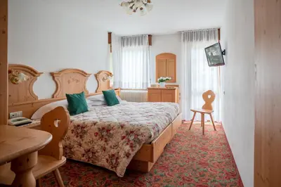 a hotel room with two beds and a television at Hotel Europa in San Martino di Castrozza