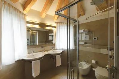 a bathroom with two sinks and a glass shower at Sayonara Nature & Wellness Hotel in San Martino di Castrozza