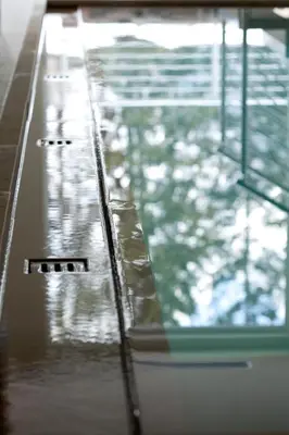 a pool of water with the reflection of a building at Sayonara Nature & Wellness Hotel in San Martino di Castrozza