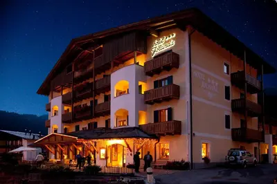a hotel building with people standing outside at night at Hotel Jolanda in San Martino di Castrozza