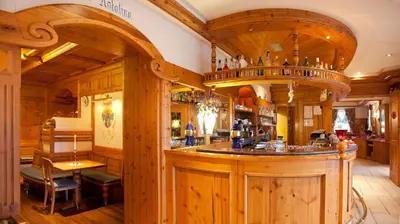 a bar in a restaurant with wooden walls at Hotel Jolanda in San Martino di Castrozza