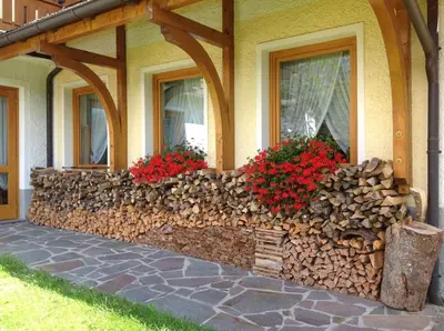 a retaining wall with firewood and flowers on a house at Hotel Jolanda in San Martino di Castrozza